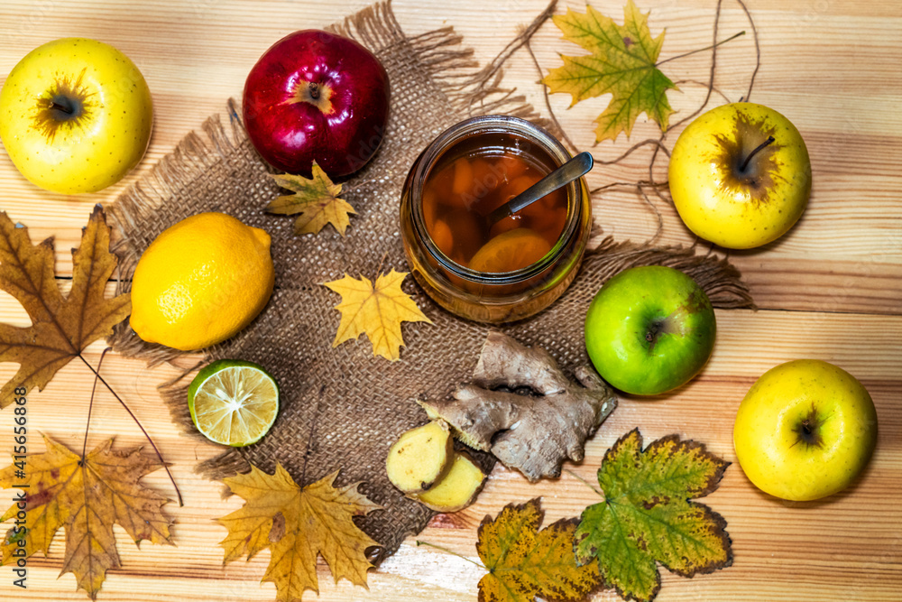 Cold homemade energy drink switchel in a mason jar next to apples, ginger and lemon on a wooden table Cold homemade energy drink switchel in a mason jar next to apples, ginger and lemon on a wooden table