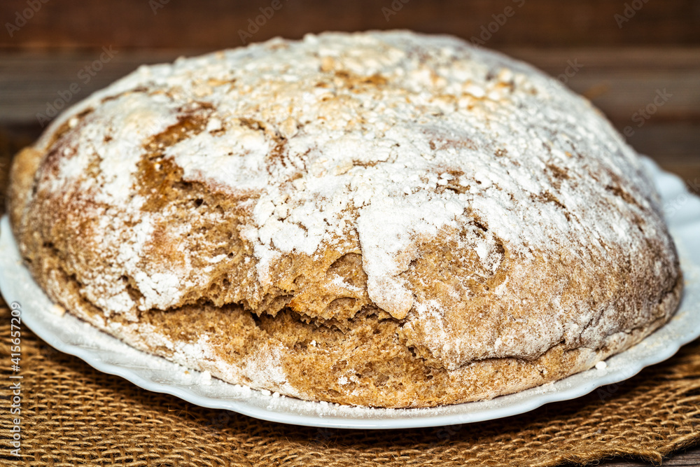 Traditional homemade bread sprinkled with flour on a wooden board