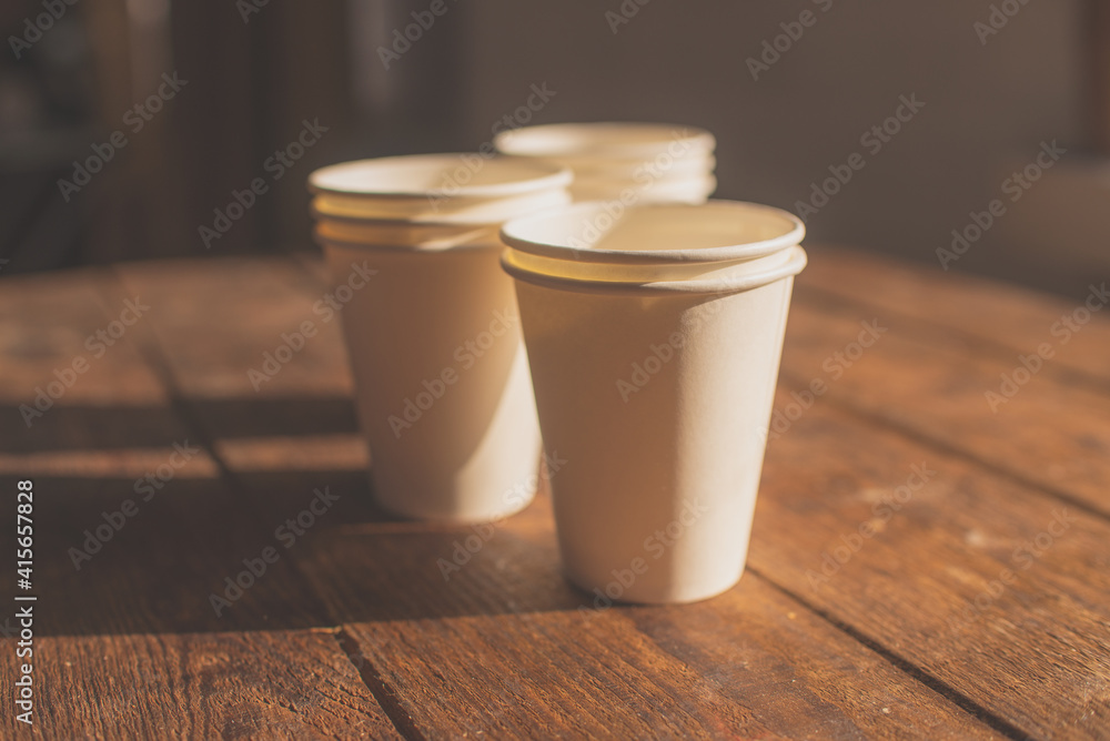 disposable cups made of white kraft paper stand on a wooden table disposable cups made of white kraft paper stand on a wooden table