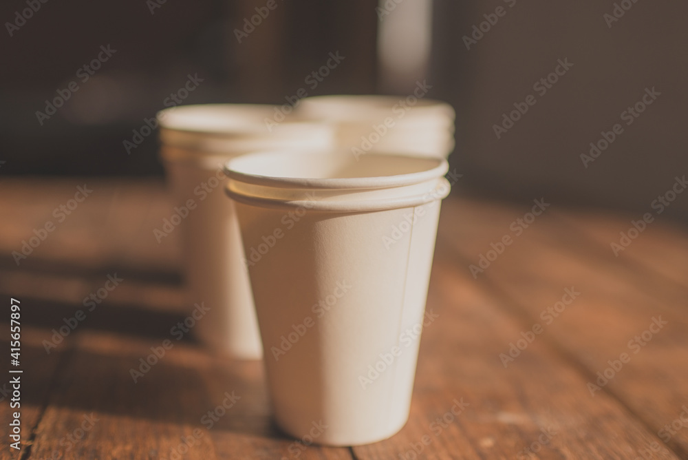 disposable cups made of white kraft paper stand on a wooden table disposable cups made of white kraft paper stand on a wooden table