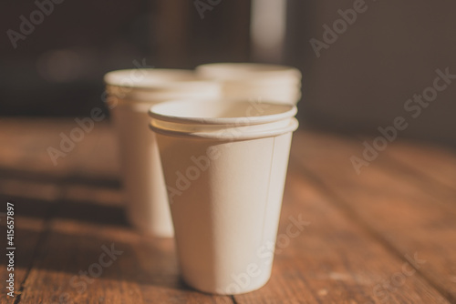 disposable cups made of white kraft paper stand on a wooden table