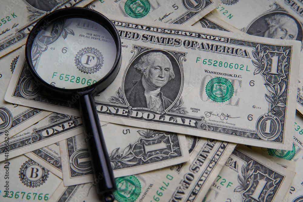 Several American one dollars on the table with a magnifying glass next to it. Bank image and commercial photo. Several American one dollars on the table with a magnifying glass next to it. Bank image and commercial photo.