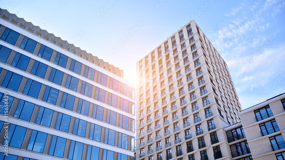 Naklejka premium Downtown corporate business district architecture. Glass reflective office buildings against blue sky and sun light. Economy, finances, business activity concept. Rising sun on the horizon.
