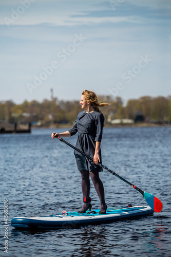 Business Woman in high heels paddling with SUP stand up paddle board