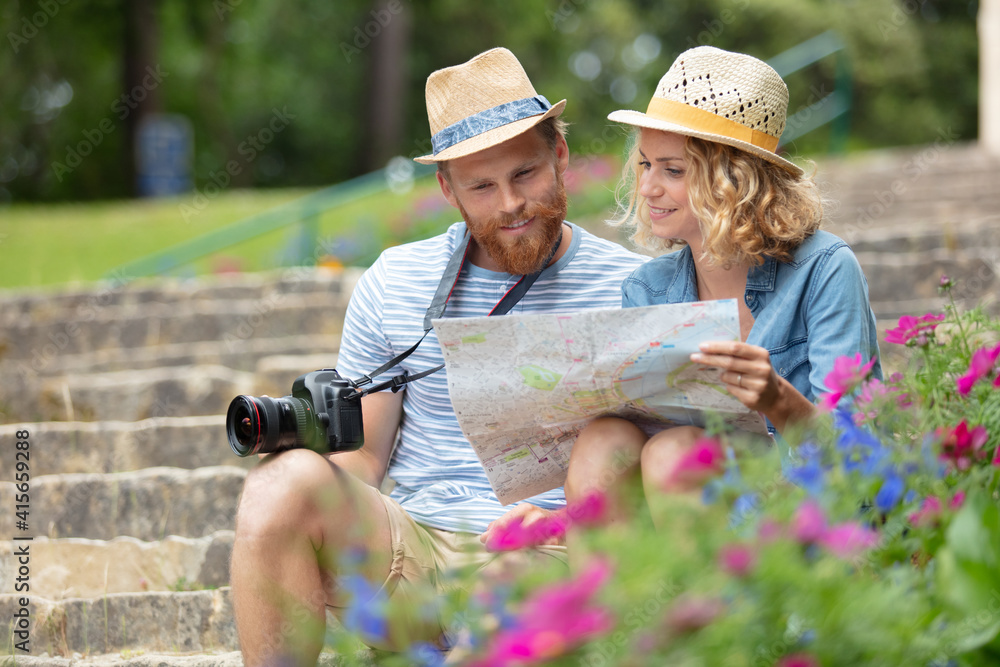 young couple tourists watching a map sitting on stairs young couple tourists watching a map sitting on stairs