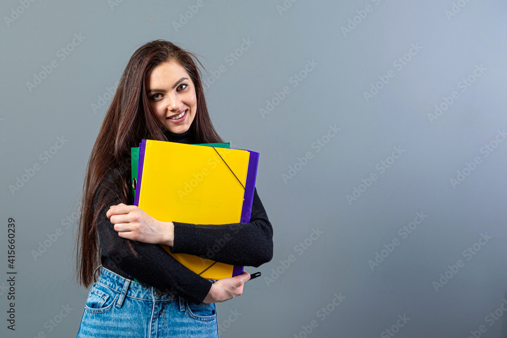 fashionable female holding a colorfuls folders with documents, isolated on dark background fashionable female holding a colorfuls folders with documents, isolated on dark background