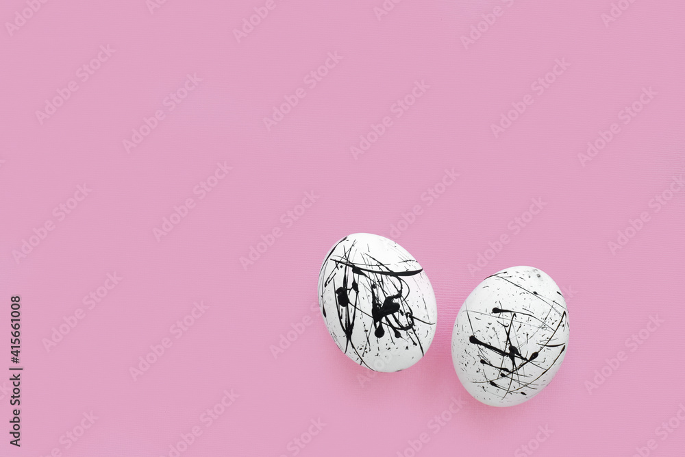 Two white eggs in black spots on a pink background with a copy of the space. Easter. Minimalism.