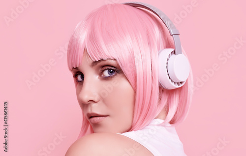 Bright sexy hipster girl with pink hair enjoys the music in headphones