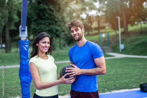Beautiful young couple enjoying together on basketball court. Bright sunny summer day.