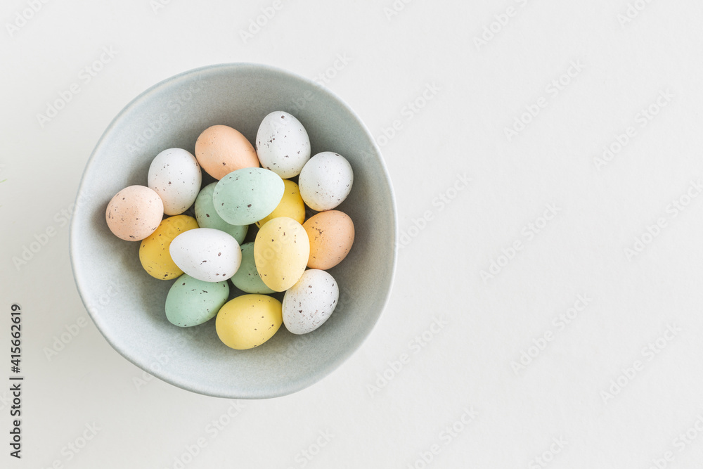 Chocolate easter egg in pastel colors in a blue bowl on a white background, flat lay with copy space Chocolate easter egg in pastel colors in a blue bowl on a white background, flat lay with copy space