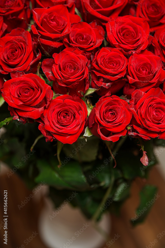 Obraz premium Beautiful red rose flower heads, photographed from above on brown wooden table. Spring flowers. Wedding, women's day, mothers day and valentines day background. Selective small depth of field.