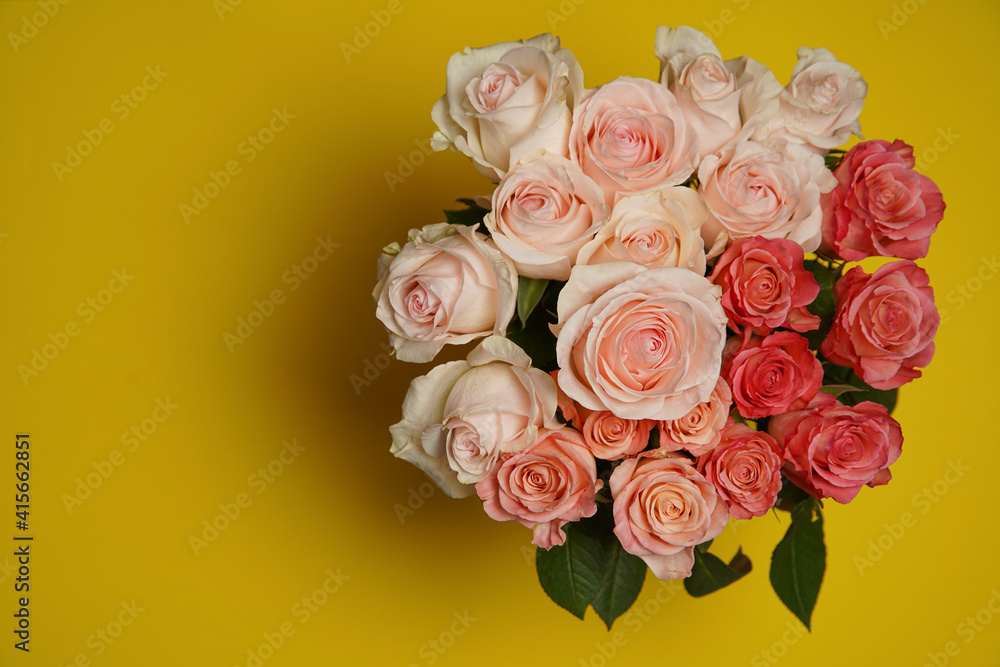 Beautiful white, red, tabby tea rose flowers in a vase photographed from above on the yellow table. Spring flowers. Wedding, mother's day and valentines day background. Selective small depth of field.