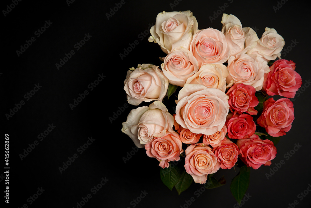 Beautiful white, red, tabby tea rose flowers in a vase, photographed from above on a black table. Spring flowers. Wedding, mother's day and valentines day background. Selective, small depth of field.