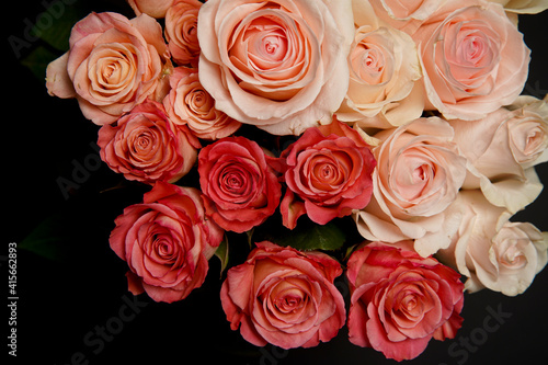 Beautiful white  red  tabby tea rose flowers in a vase  photographed from above on a black table. Spring flowers. Wedding  mother s day and valentines day background. Selective  small depth of field.
