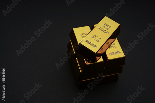 A pile of gold bar a black background. Shiny precious metals for investments or reserves.