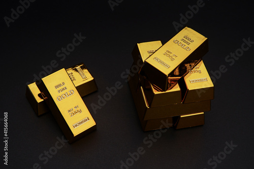A pile of gold bar a black background. Shiny precious metals for investments or reserves.