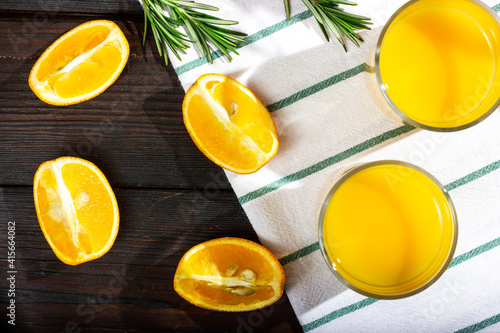 Orange slices on a dark wooden table. A glass of orange juice - top view. The process of making orange juice.