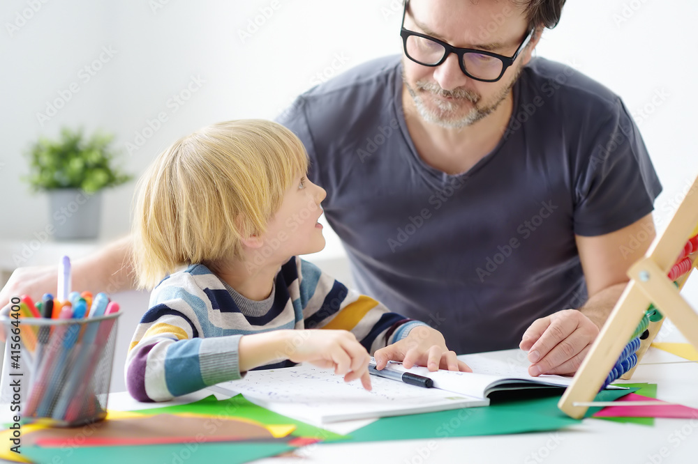 Father helping child do his homework at home. Homeschooling, distance learning, online studying, remote education for kids during quarantine is a problems for parents. Tutor teaching boy with ADHD. Father helping child do his homework at home. Homeschooling, distance learning, online studying, remote education for kids during quarantine is a problems for parents. Tutor teaching boy with ADHD.