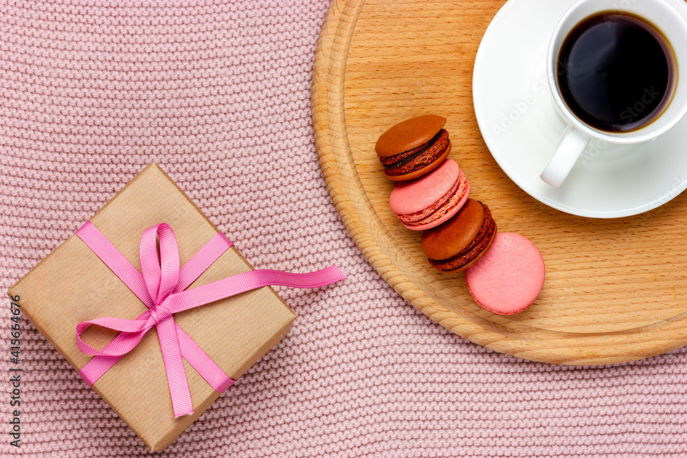 Gift in a box tied with a pink ribbon. Cup of coffee and macaroon. Romantic plot. Gift in a box tied with a pink ribbon. Cup of coffee and macaroon. Romantic plot.