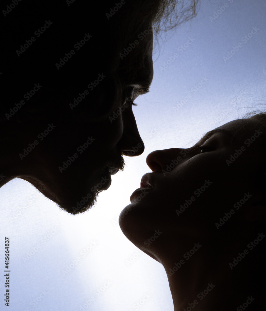 portrait of a romantic couple kissing when illuminated from a window or door. portrait of a romantic couple kissing when illuminated from a window or door.