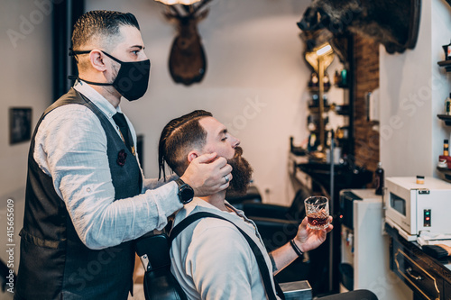 Young good looking hipster man visiting barber shop. Trendy and stylish beard styling and cut.