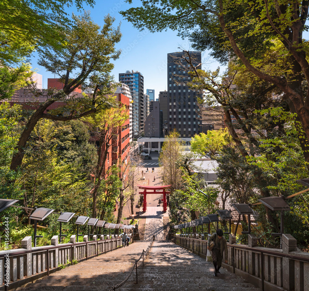 tokyo, japan - april 13 2019: Top of the famous stairs of success dedicated to the samurai Magaki Heikurou and leading to the red torii gate of the Atago shrine with people climbing the steep steps.