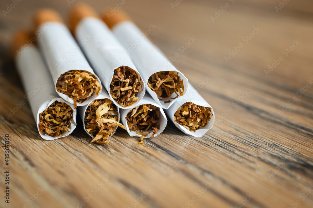 Close up of a hndmade smoking cigarettes on wooden background Close up of a hndmade smoking cigarettes on wooden background