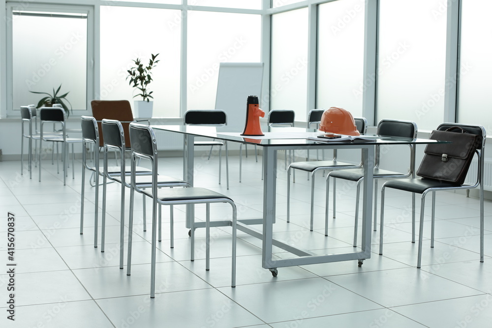 Fototapeta premium Loudspeaker construction helmet chairs diary briefcase phone glass table in a bright office