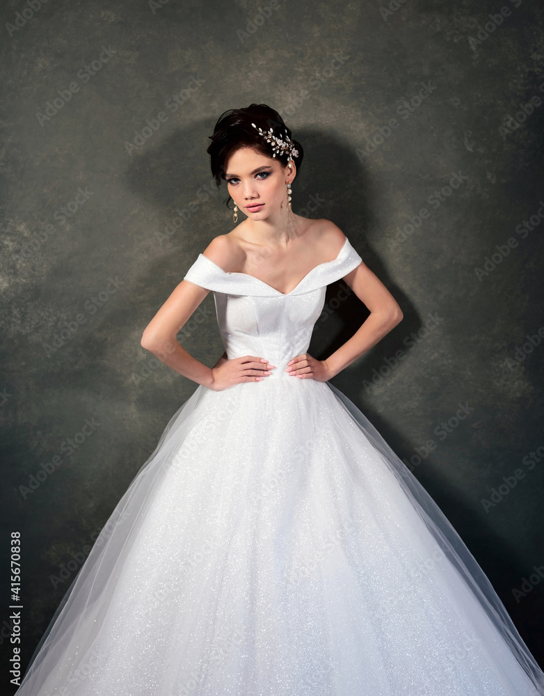 Attractive young model in a white dress with jewelry in her hair. Beautiful bride with wedding makeup and fashion hairstyle Attractive young model in a white dress with jewelry in her hair. Beautiful bride with wedding makeup and fashion hairstyle