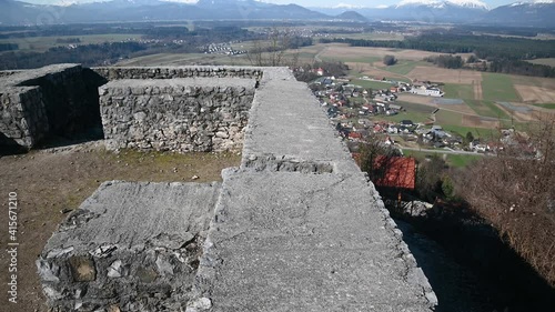 Smlednik castle defensive walls on sunny day at winter in Slovenia. Elevated view of flatland basin with Alps mountains in the distance. Farming fields and forest in lowland. Wide angle, tilt up photo