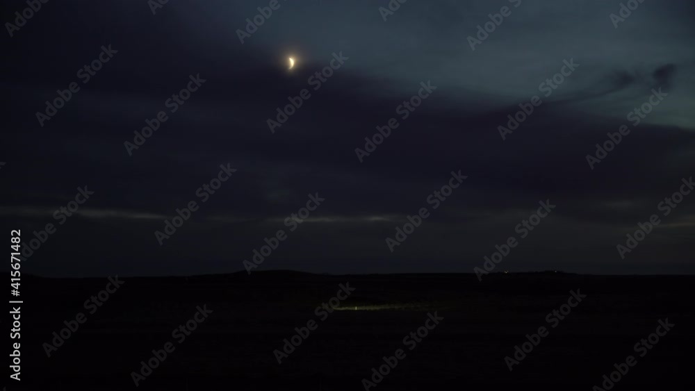 Truck driving under crescent moon at dusk Iceland Truck driving under crescent moon at dusk Iceland