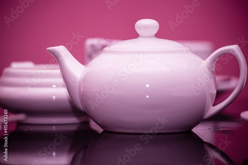 A porcelain teapot with cups is on the table in the restaurant. Purple ceramic tableware. The concept of tea drinking.