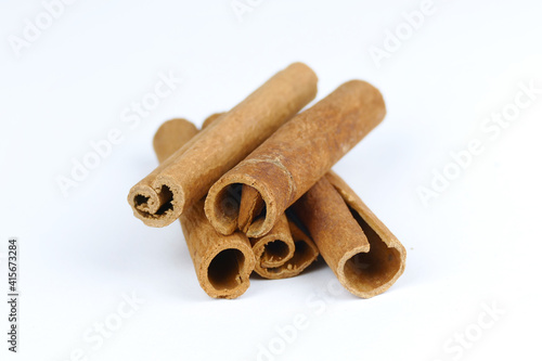 Cinnamon sticks isolated on a clean white background, close-up of dry brown aromatic spice rolls with detailed bark texture, organic culinary ingredient asset for food photography and design layouts