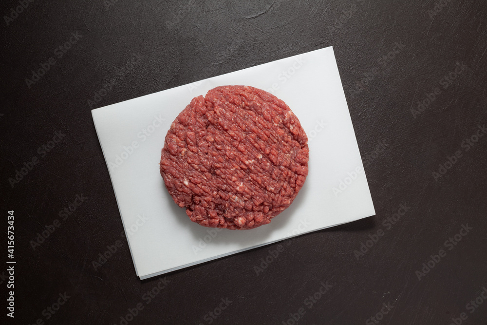 Juicy homemade hamburger, close-up. Raw minced meat on a dark textured background, top view Juicy homemade hamburger, close-up. Raw minced meat on a dark textured background, top view