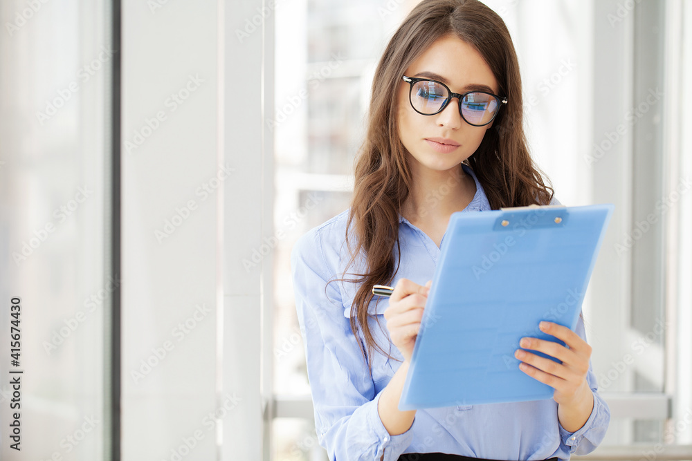 Young business woman with clipboard in the office. Young business woman with clipboard in the office.