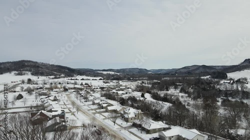 Slow pan just over the tree line of a rural suburban single road neighborhood in a snow-covered valley photo