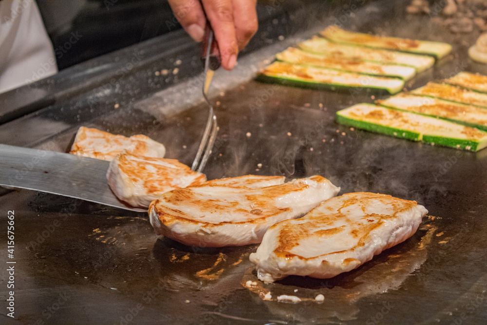 Chef cooking chicken breast and vegetables on grill. Meat on the grill.