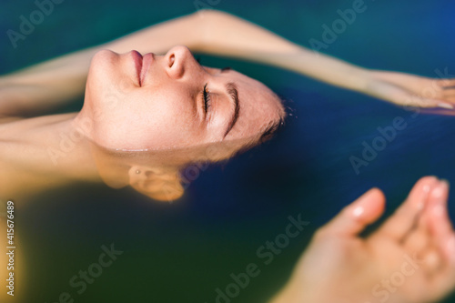 Beautiful woman floating in tank filled with dense salt water used in meditation, therapy, and alternative medicine. . photo