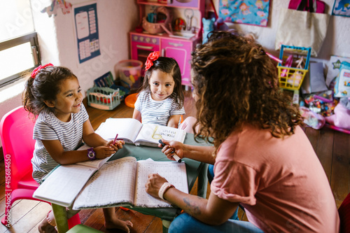 Photos hispanic mother with her daughtersvat home in homeschooling concept in Mexico