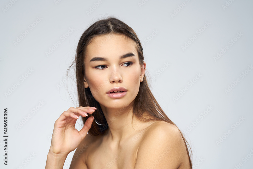 Pretty brunette naked shoulders long hair close-up light background Pretty brunette naked shoulders long hair close-up light background
