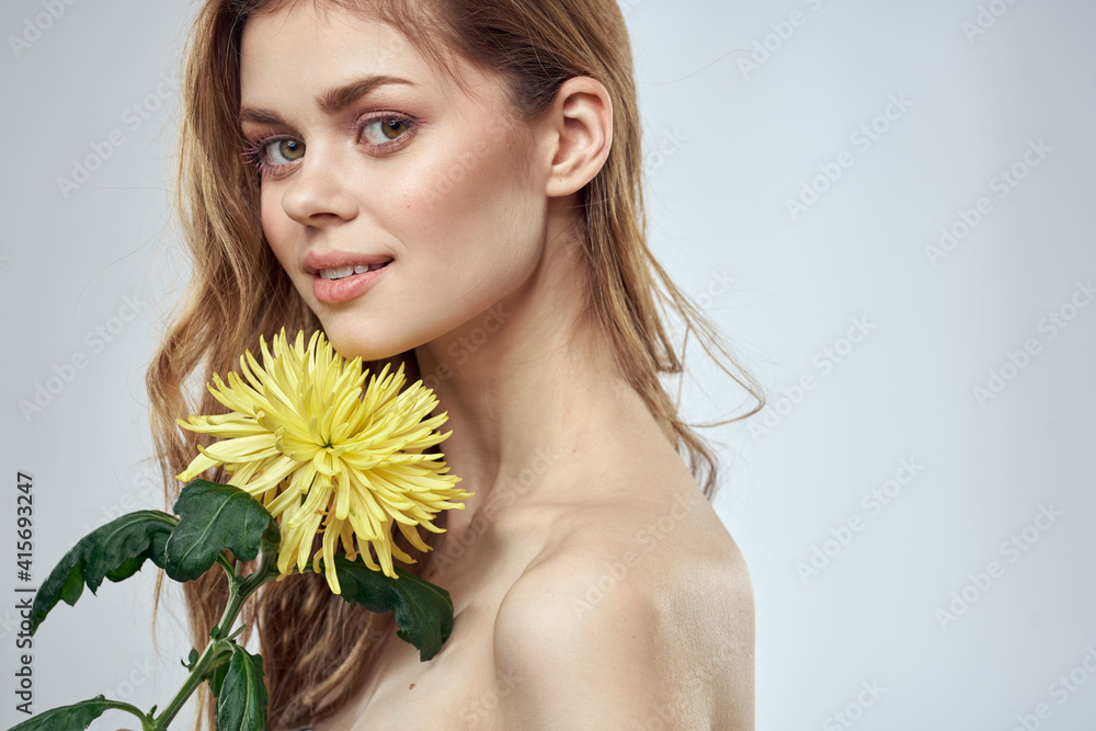 Portrait of a beautiful woman with a yellow flower on a light background charming smile model red hair Portrait of a beautiful woman with a yellow flower on a light background charming smile model red hair