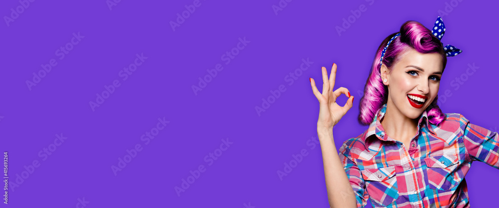 Pin up girl. Portrait photo of excited happy smiling purple hair woman showing ok hand sign gesture. Retro and vintage concept. Violet color background. Caucasian model posing at studio.