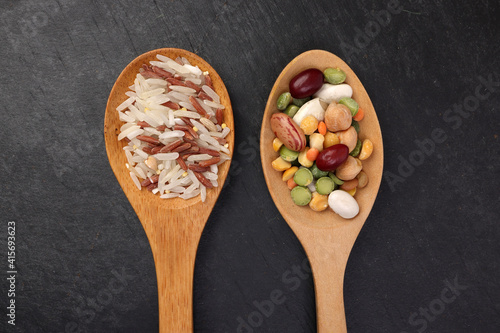 Mixed beans multi grain low glycaemic index healthy rice grain basmati millet buckwheat red rice in wooden spoon on black background photo