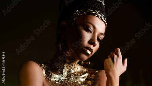 woman queen Cleopatra art photo, creative makeup Black hair braids and carnival ethnic costume on black background