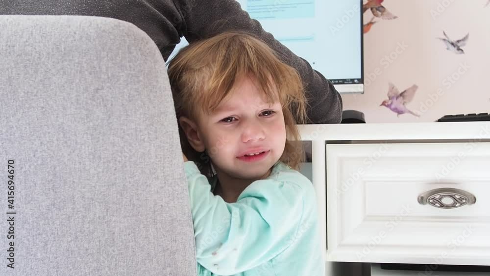 Crying female kid attracts the attention of her mother who works at the computer. Career mom concept, problems associated with working at home Crying female kid attracts the attention of her mother who works at the computer. Career mom concept, problems associated with working at home