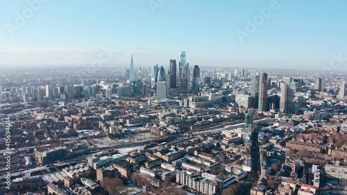 high dolly back drone shot over city of london skyscrapers from tower hamlets clear day after snow photo