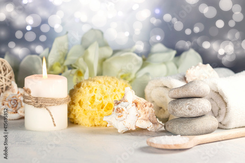 Massage stones  natural sea sponge  seashell  burning candles  rolled towels  sea salt  orchid flowers  abstract lights. Spa resort therapy composition