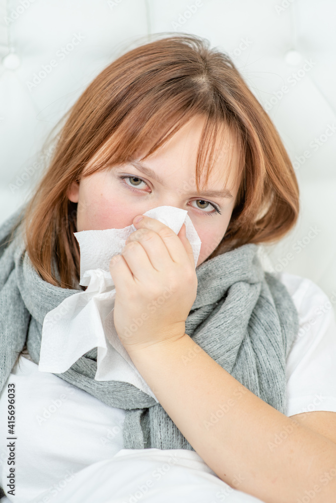 Sick girl blowing her nose in a handkerchief