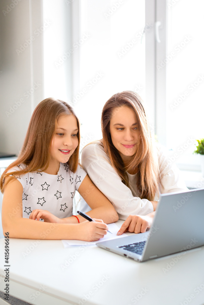 Online education concept. Mom helps her daughter do her homework online. They looking to laptop monitor.