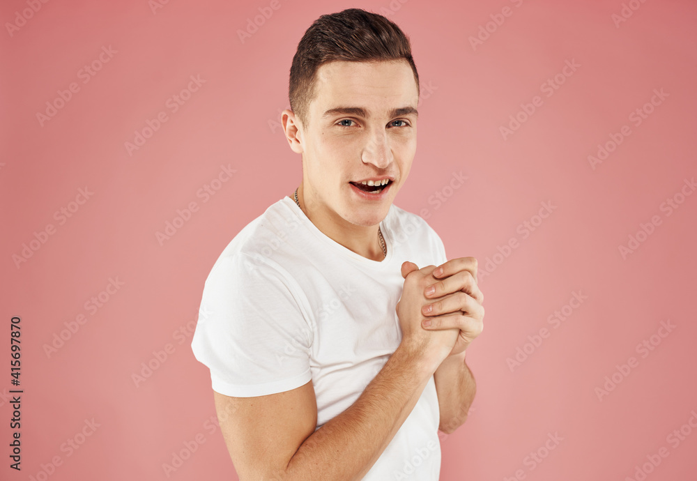 Guy on a pink background gesturing with his hands in a white t-shirt cropped view Guy on a pink background gesturing with his hands in a white t-shirt cropped view